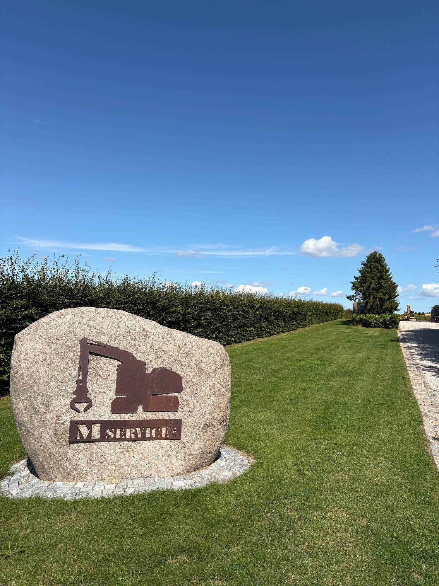 M-Service – indkørsel med firmaets logo i granitsten